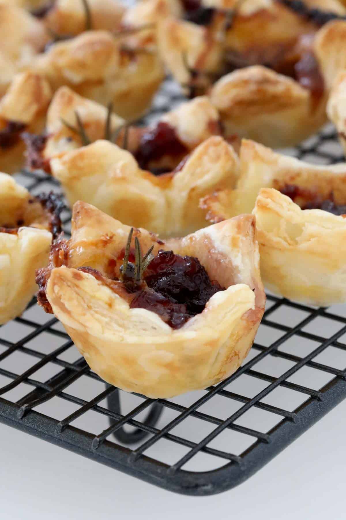 Brie and cranberry puff pastry bites on a wire cooling rack.