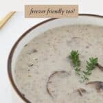 A bowl of creamy mushroom soup garnished with thyme sprigs.