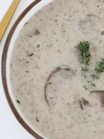 A bowl of mushroom creamy soup with thyme.