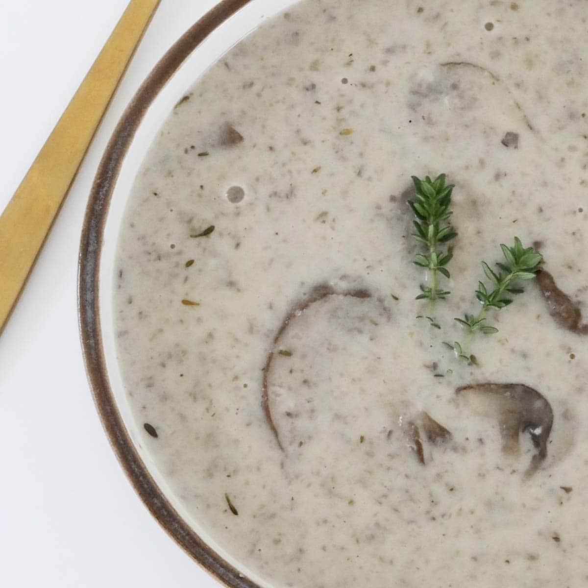 A bowl of mushroom creamy soup with thyme.