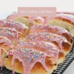 Sweet sticky pink iced finger buns on a wire rack.