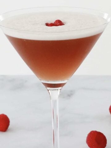 A cocktail glass filled with a French Martini and topped with a raspberry.