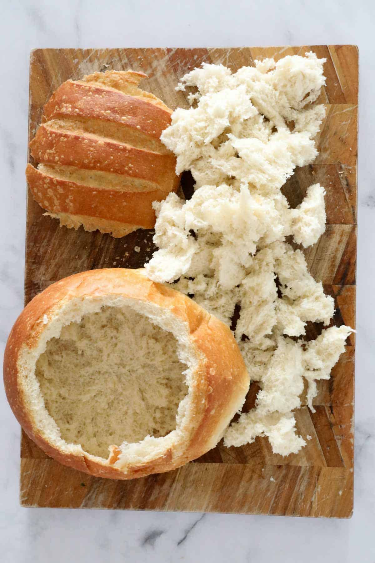 The top of a cob loaf cut off and hollowed, with the bread inside taken out in small pieces.