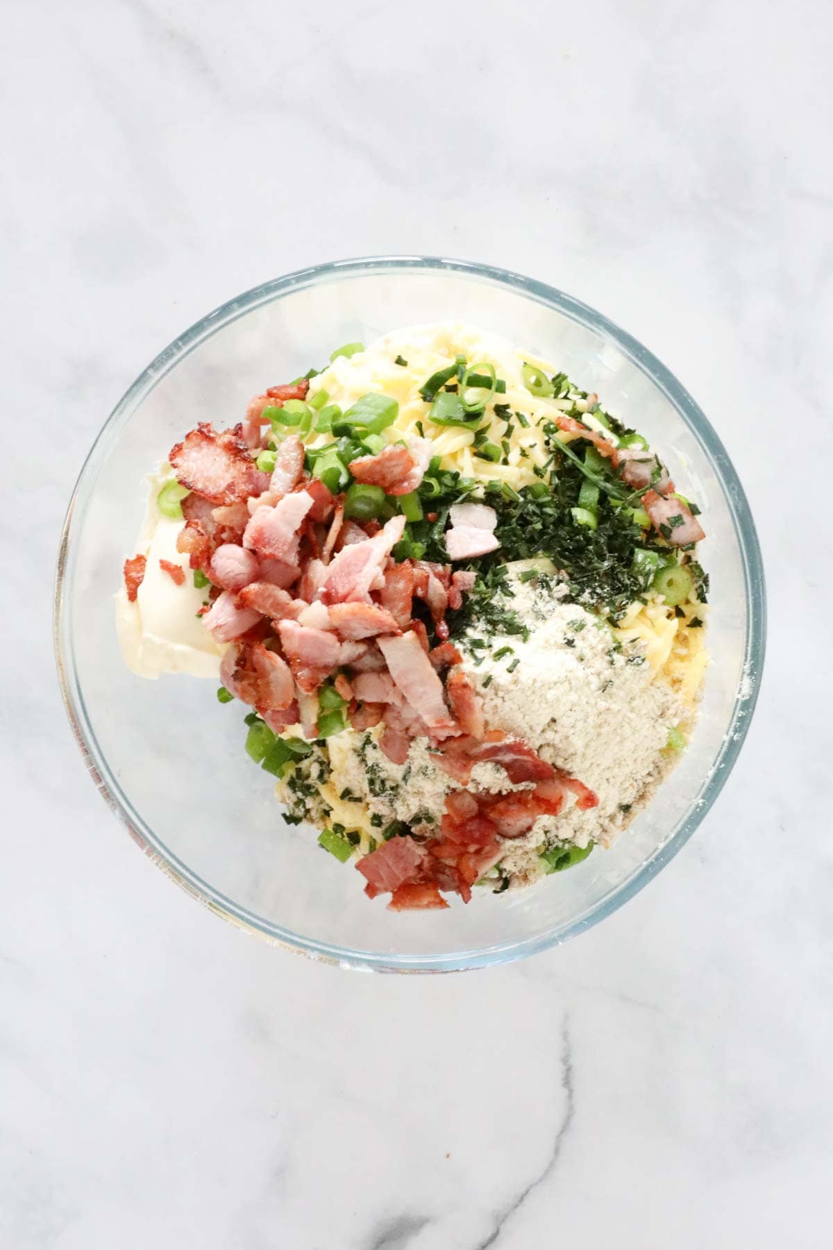 Bacon, cream cheese, sour cream, grated cheese, mayonnaise, chives and spring onions in a mixing bowl.