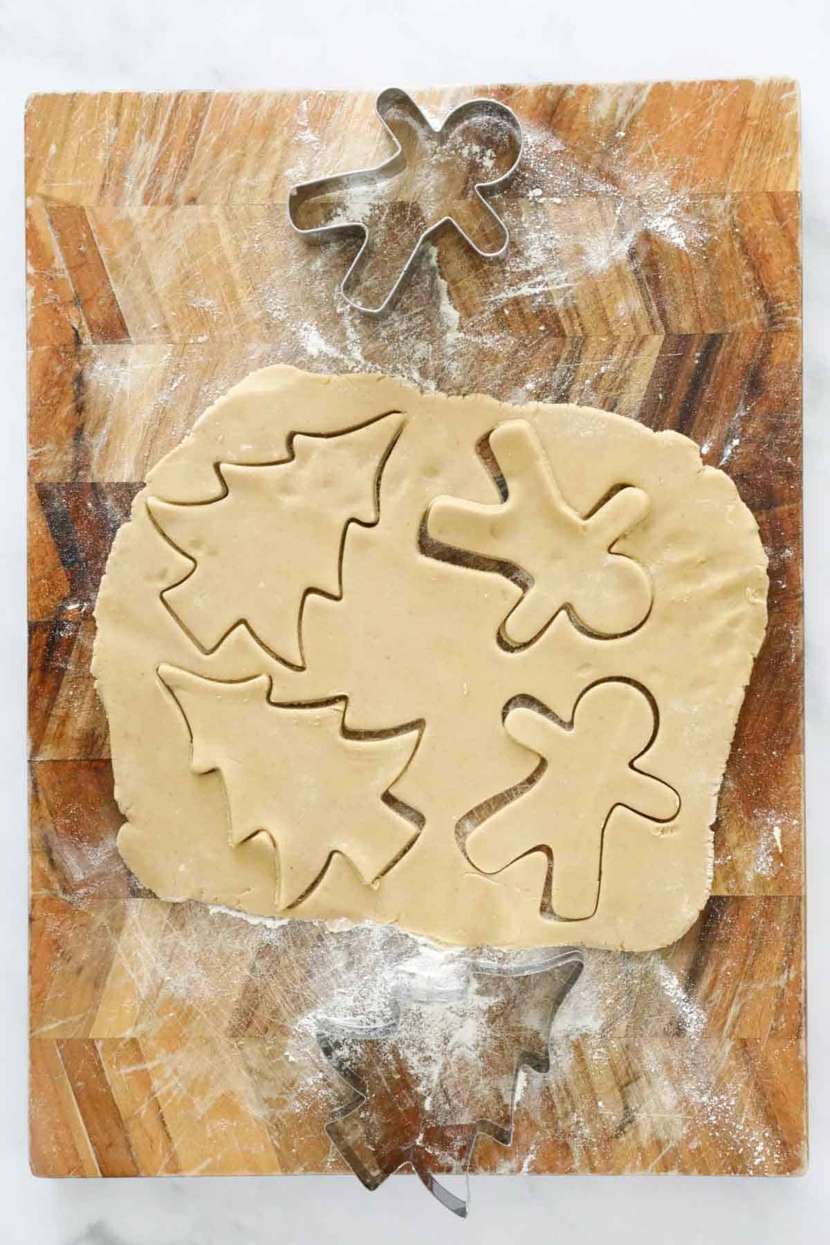 Christmas shapes being cut out of gingerbread dough.