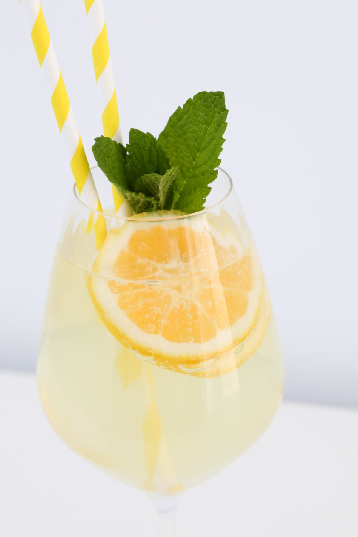 Limoncello prosecco cocktail in glass garnished with lemon slices and fresh mint.
