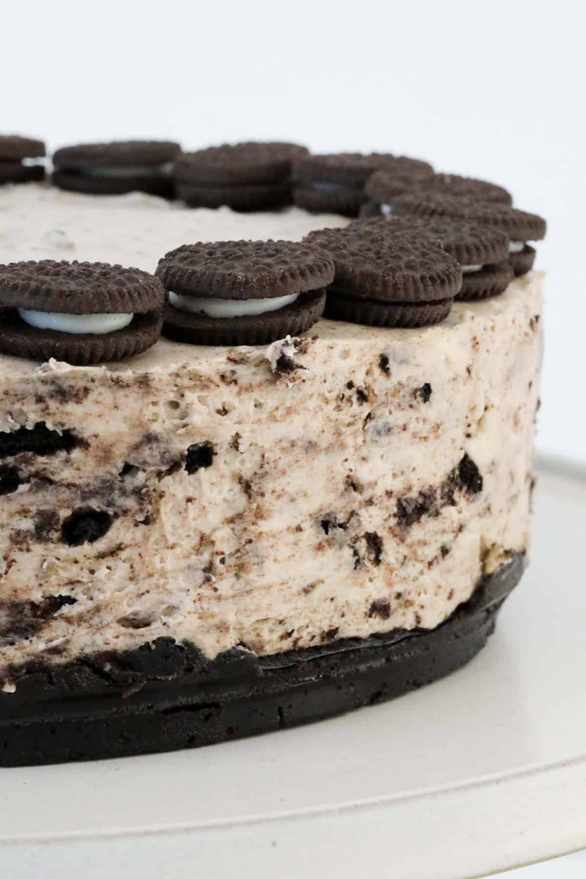 A side view of a cheesecake showing the chocolate biscuit base, the cookies & cream filling, and mini Oreo's decorating the top.