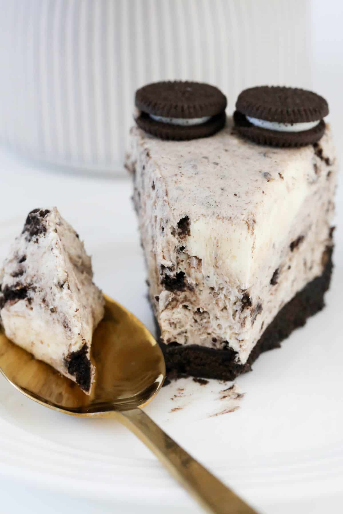 A slice of Oreo cheesecake with a spoonful removed.