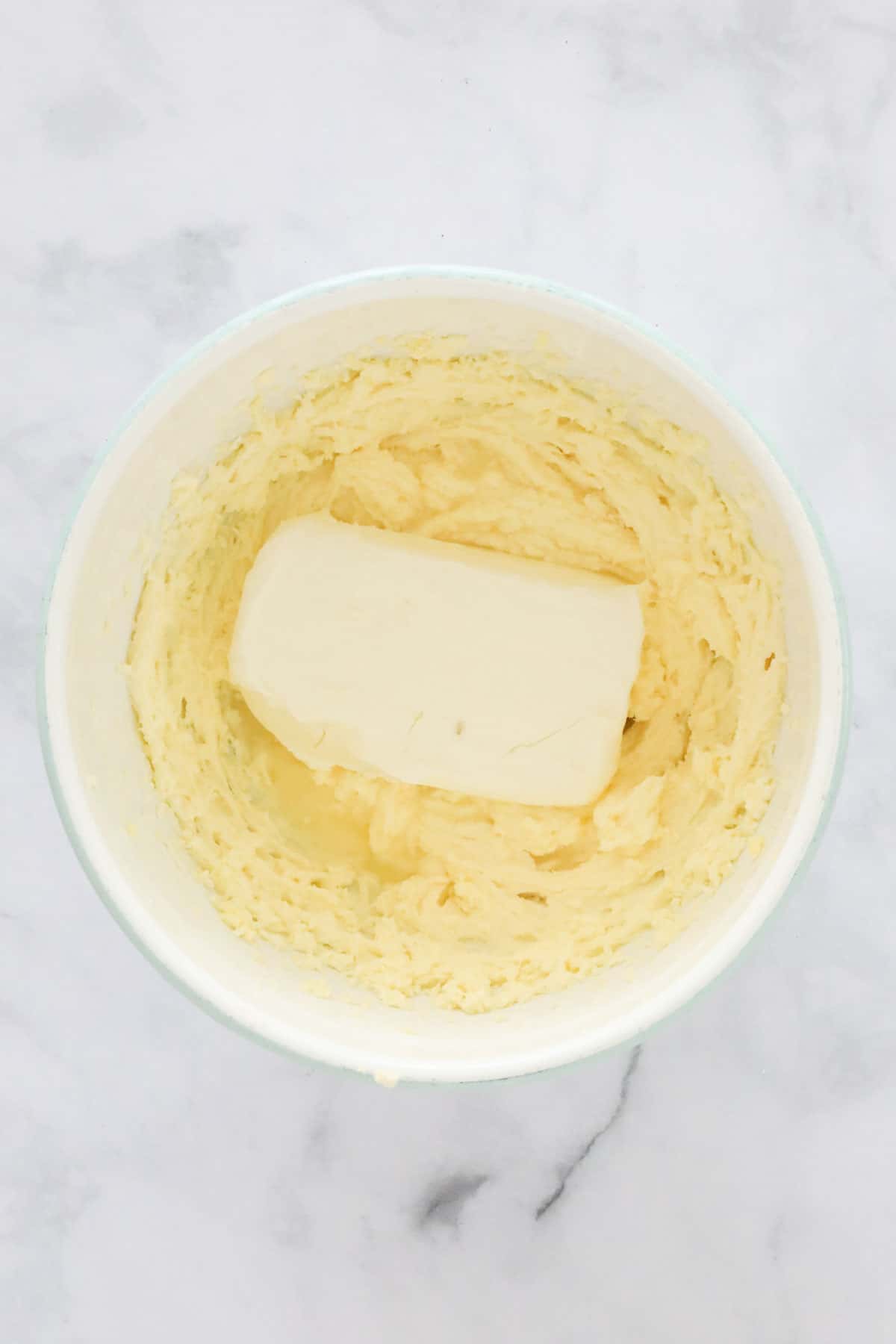 A block of cream cheese added to the mixing bowl.