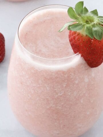 A creamy, fruity strawberry cocktail with a fresh strawberry on top.