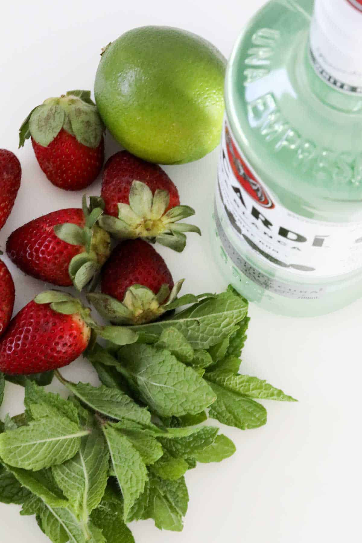 Bacardi rum, fresh mint leaves, lime and strawberries, ingredients used to make the cocktail.
