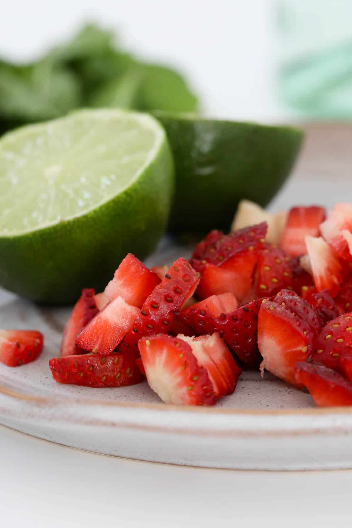 Finely diced strawberries and halved limes on a plate.