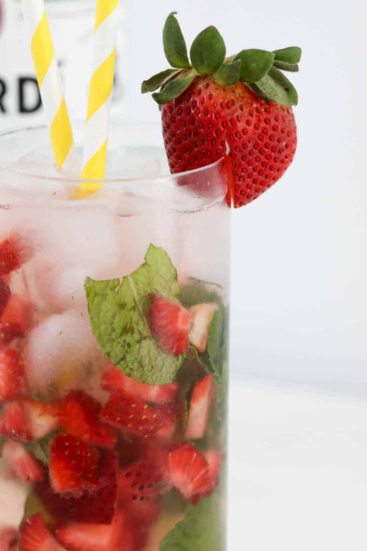 Close up of a refreshing cocktail full of chopped strawberries in a glass.