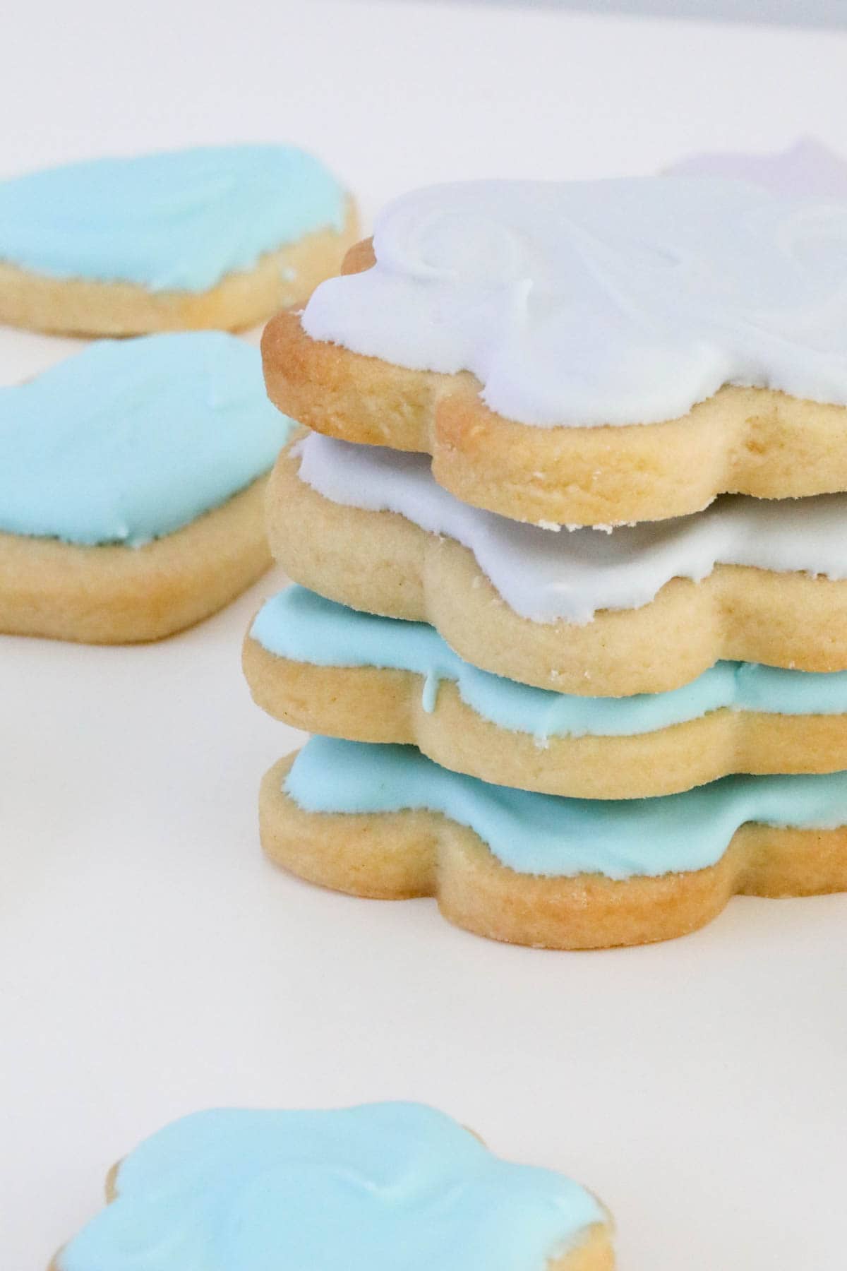 Side view of a stack of 4 iced flower shaped biscuits.