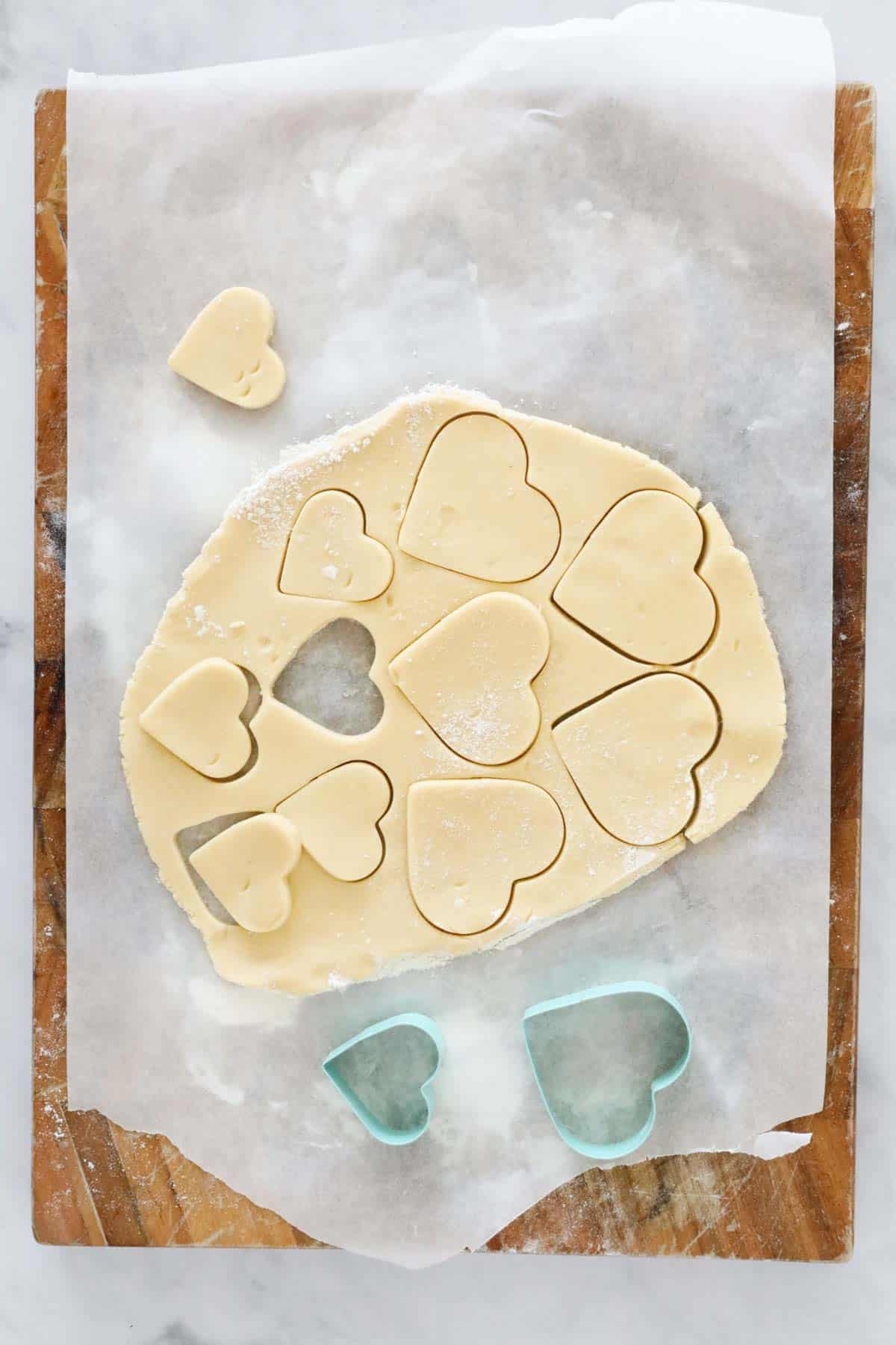 Rolled out dough with heart shapes cut out with cookie cutters.