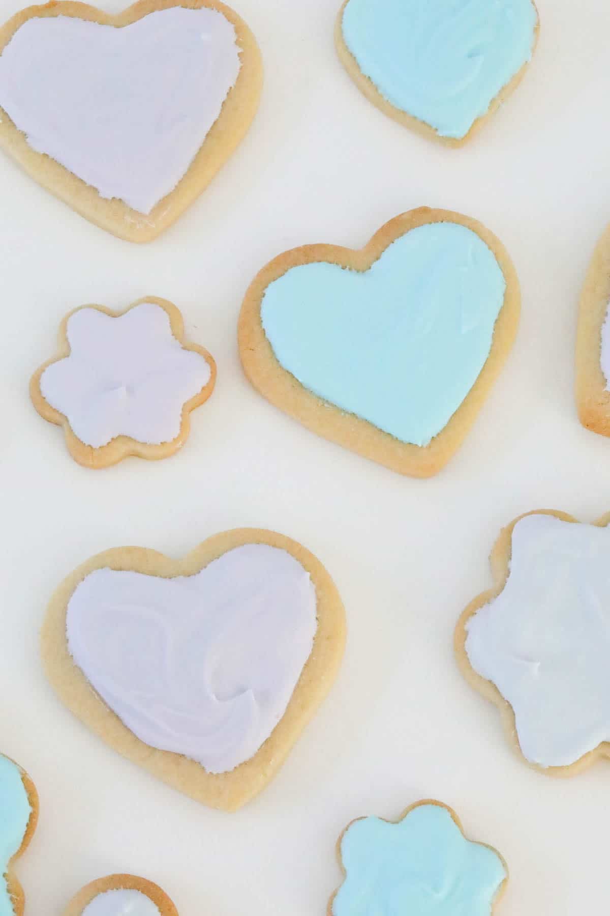 Sugar cookies in various shapes decorated with pale pink and blue royal icing.