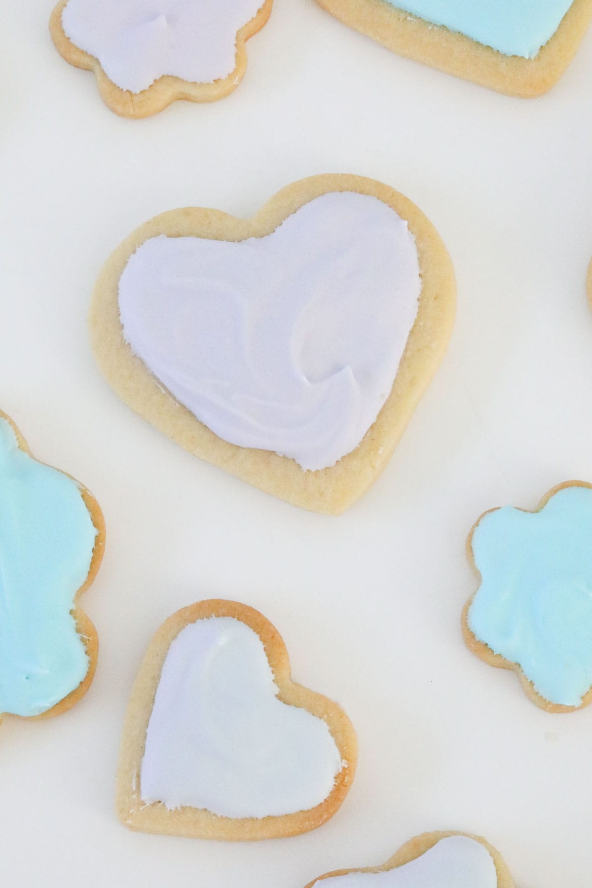 Close up of an iced sugar cookie heart, with other flower shaped cookies just visible.