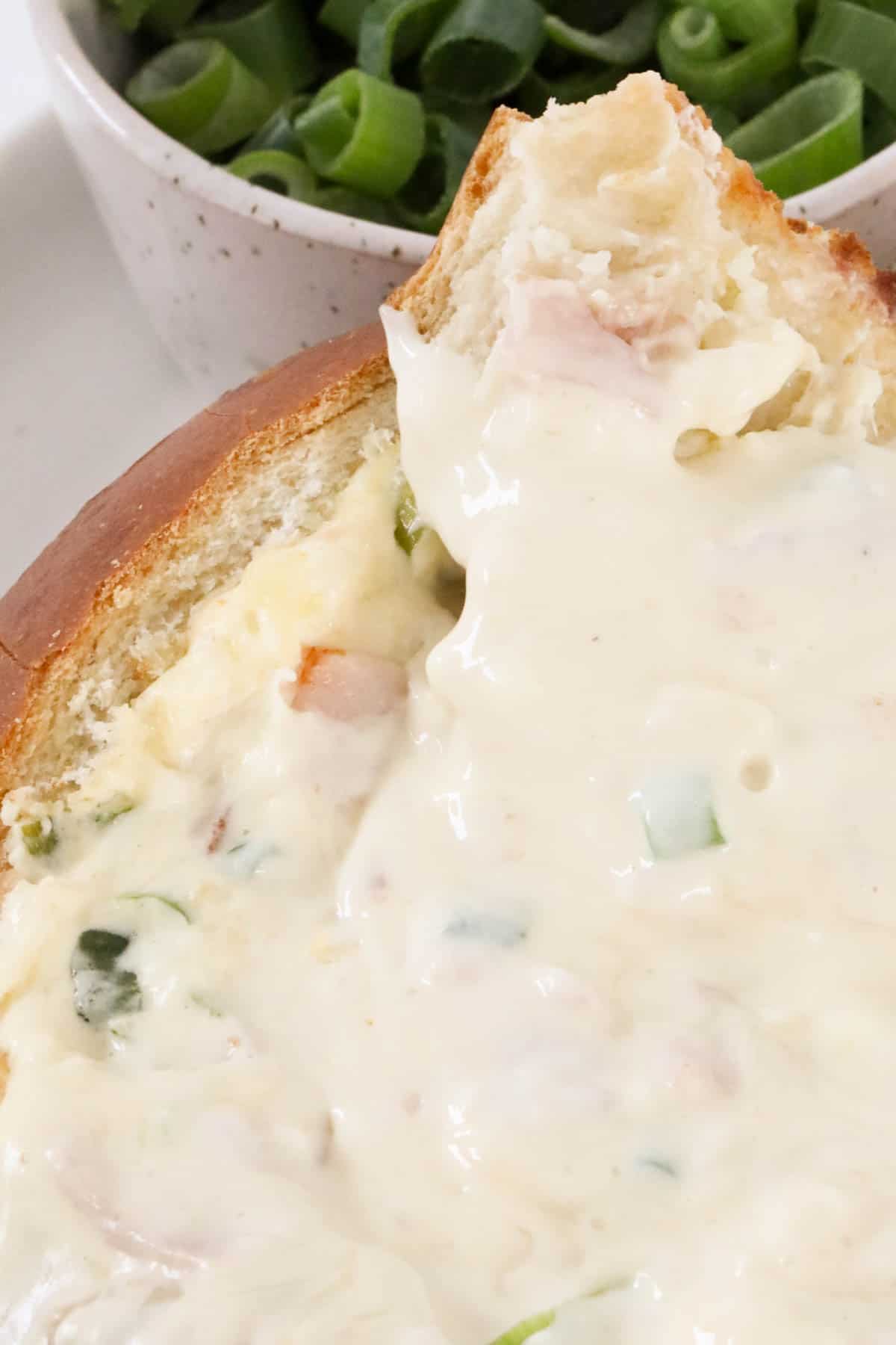 A close up of baked bacon cheese dip in the cob loaf.