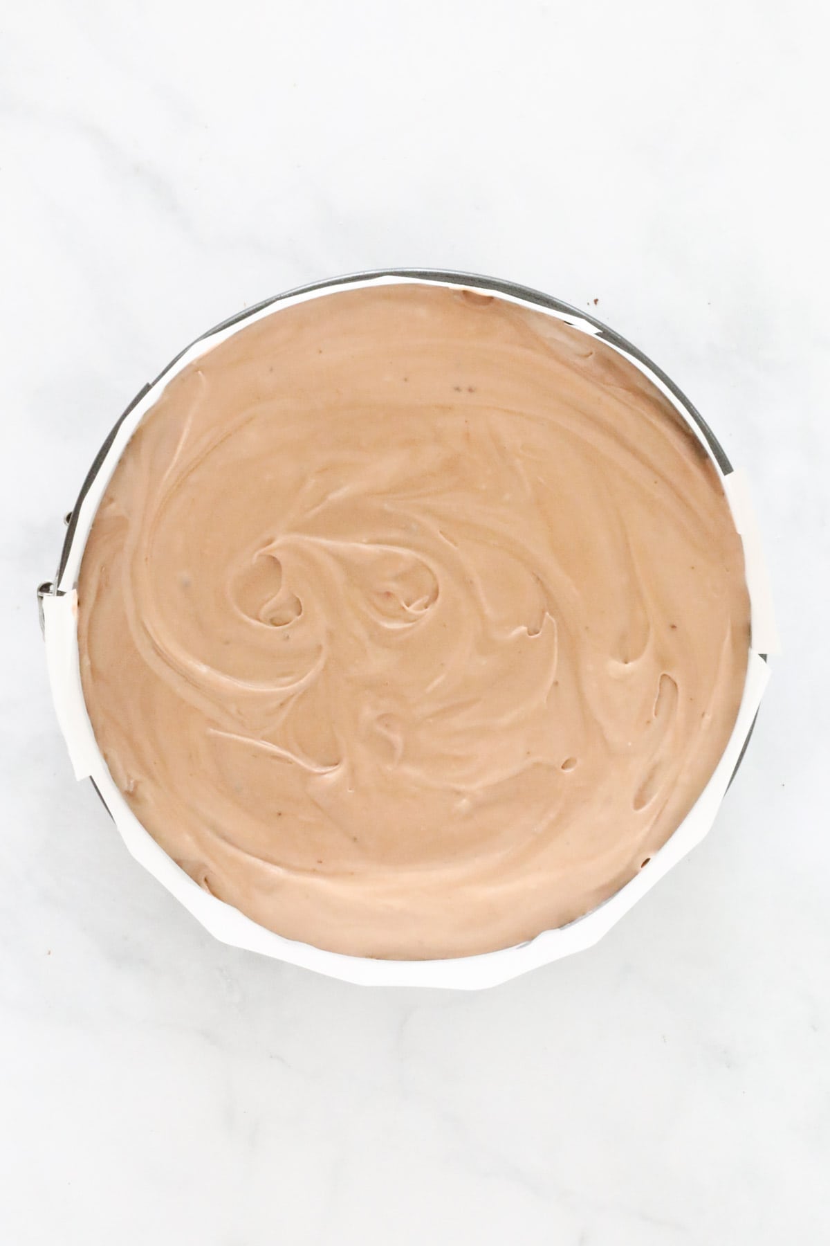 Chocolate cheesecake filling spread over the biscuit base in springform tin.