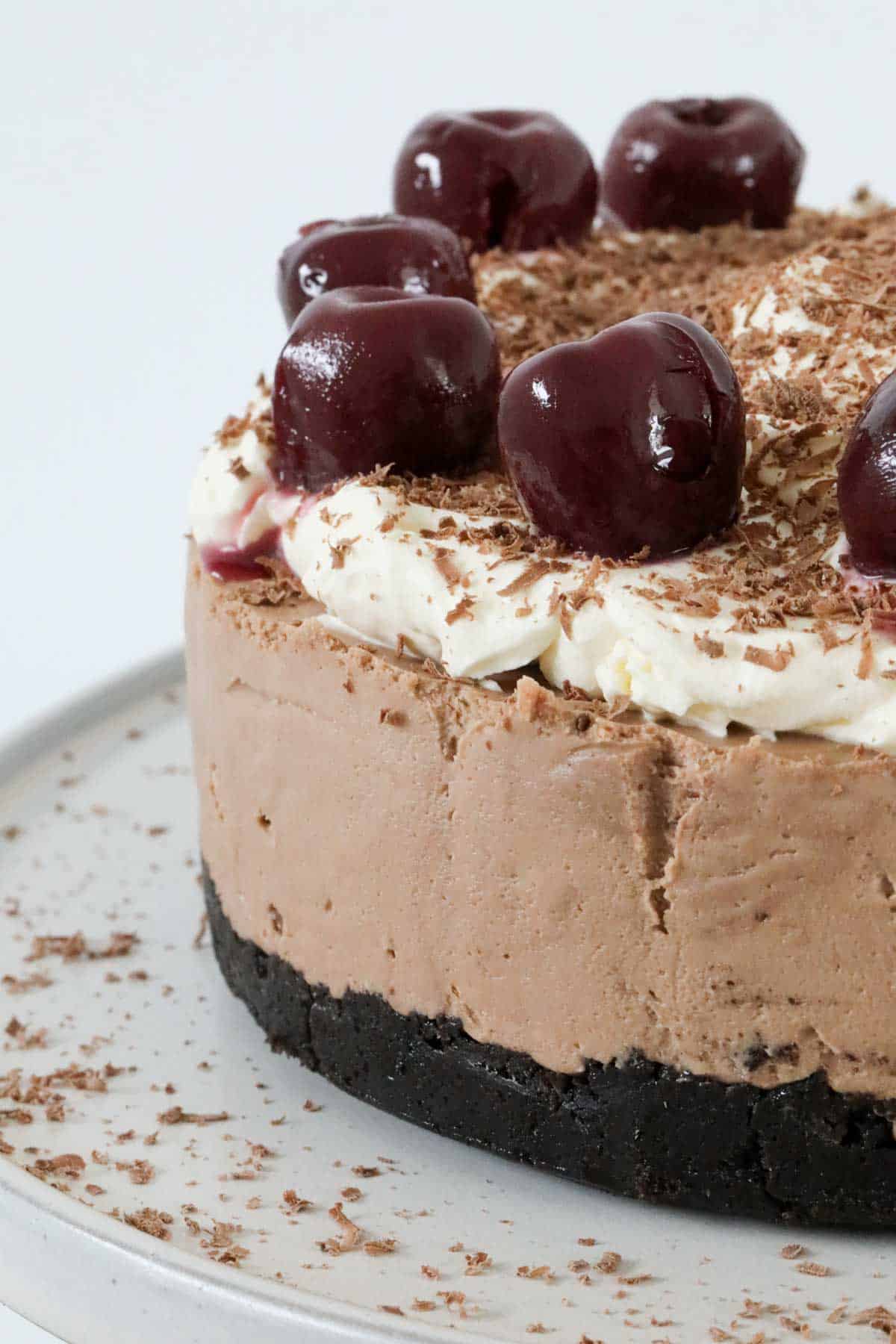 A close up of the side of a decorated Black Forest cheesecake.