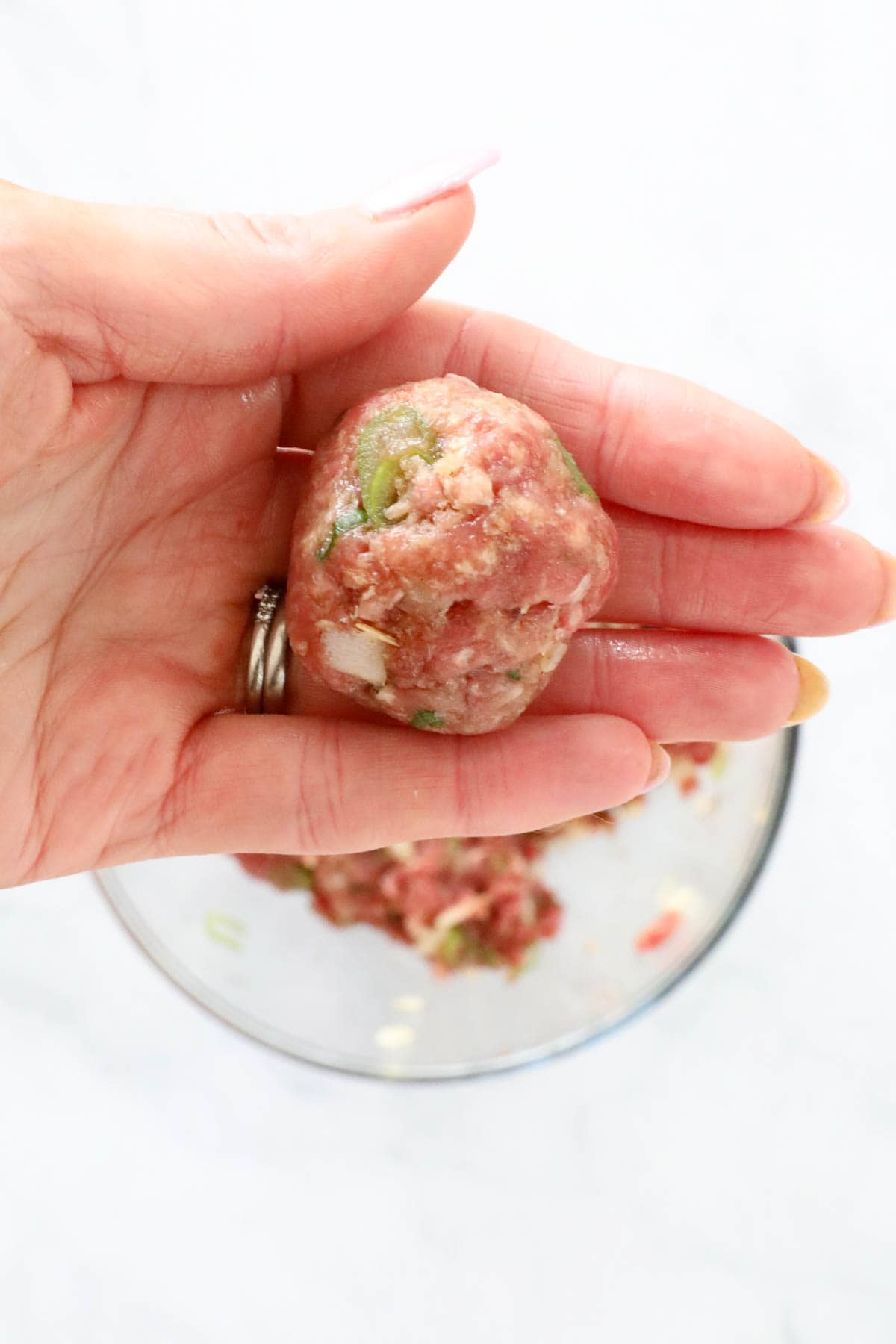 A hand holding a rolled meatball.