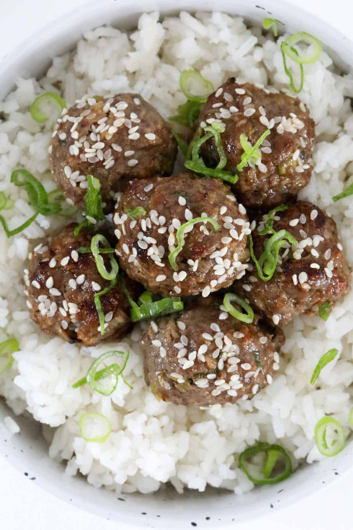 The cooked mince balls served with rice and sprinkled with sesame seeds and spring onions.