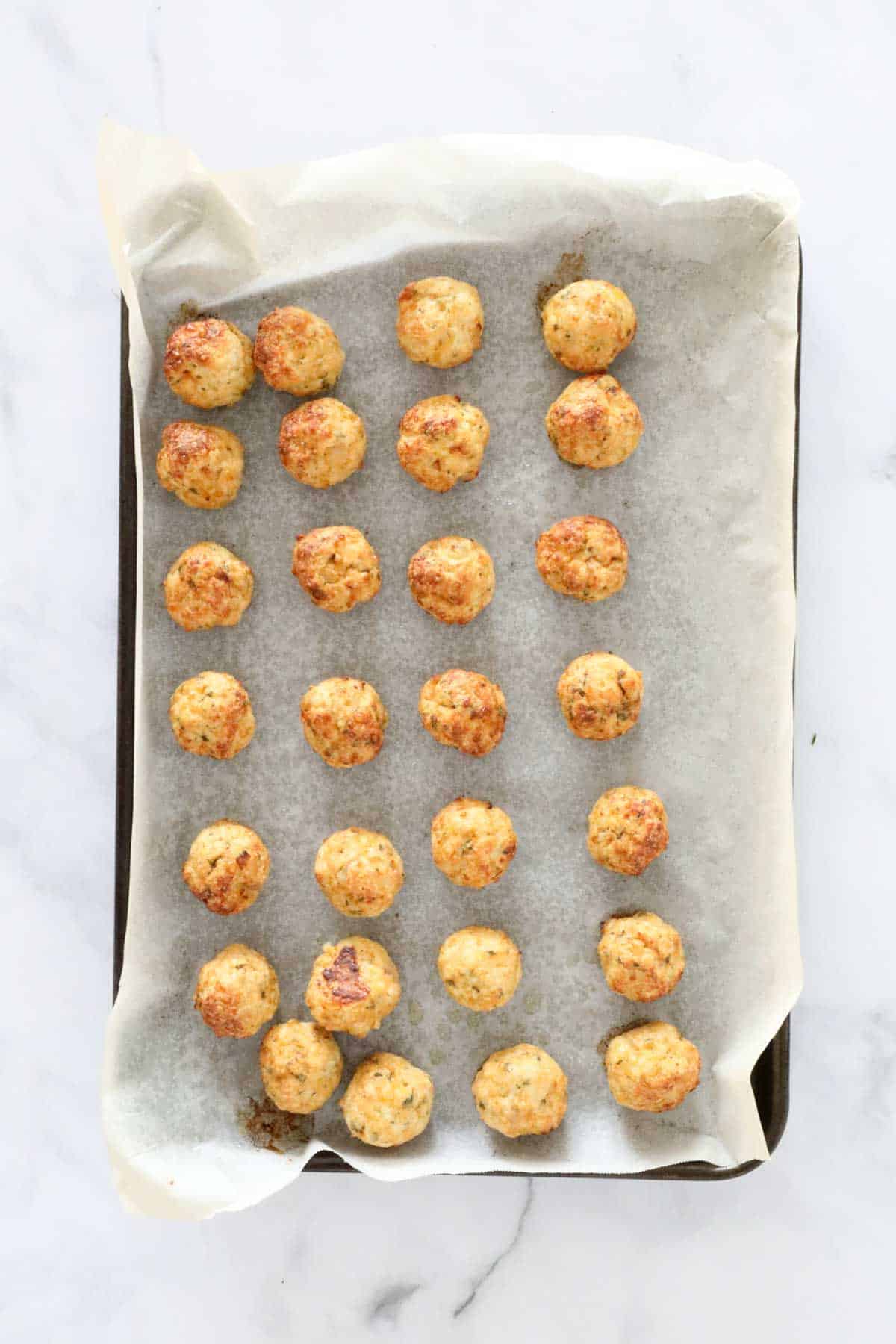 Golden baked meatballs on a baking tray.