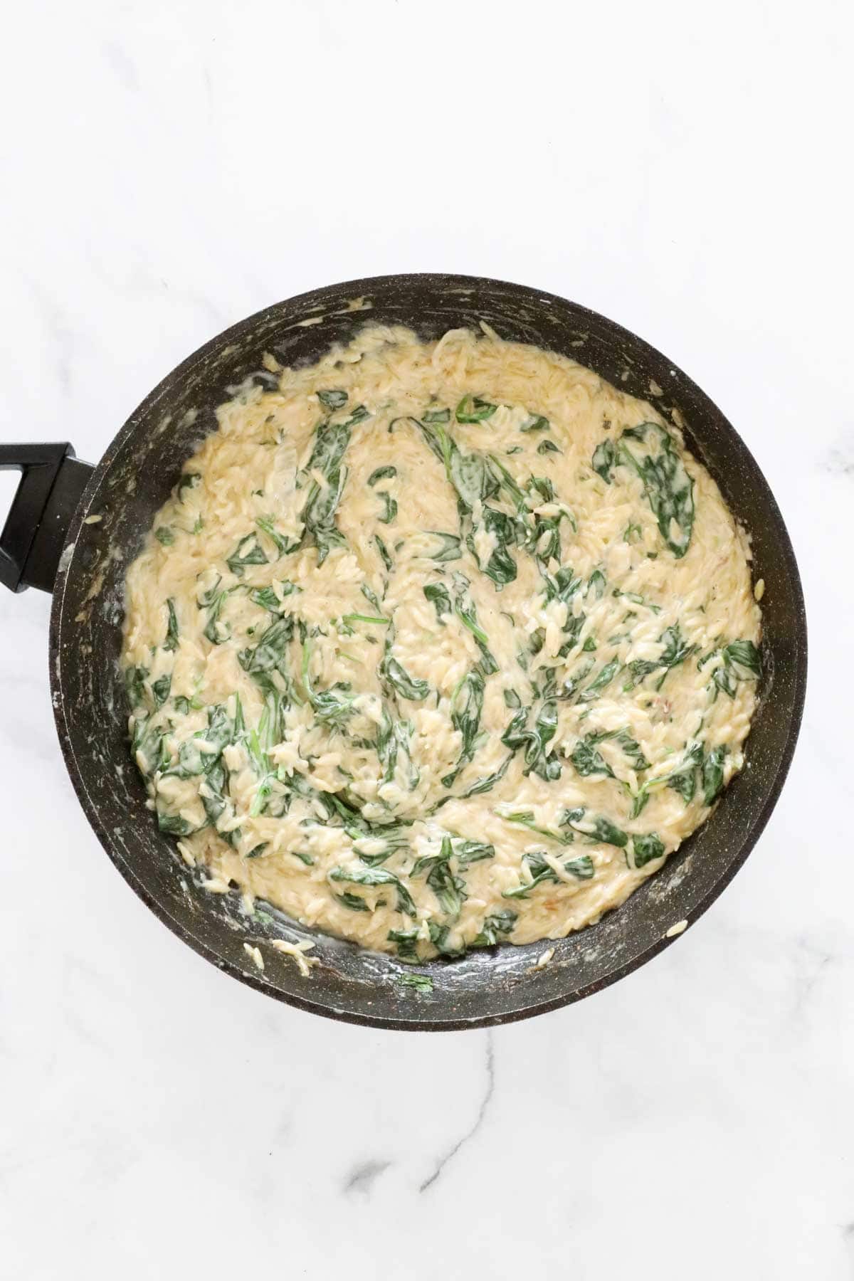 Creamy lemon and spinach risoni in a frying pan.
