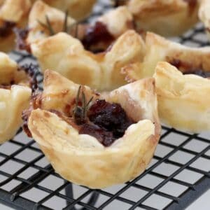 A mini pastry filled with cranberry jam, brie cheese and a sprig of rosemary.