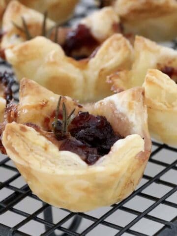A mini pastry filled with cranberry jam, brie cheese and a sprig of rosemary.