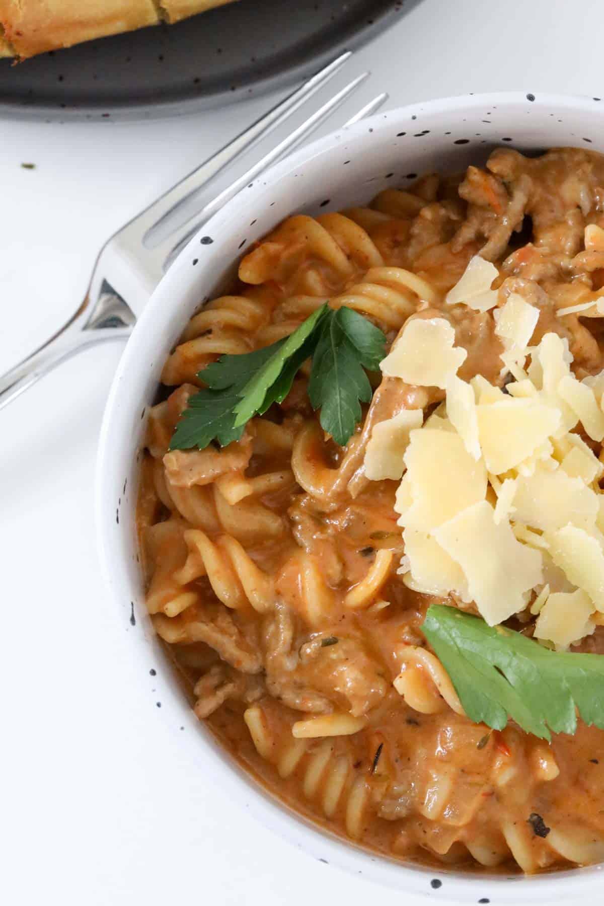 Creamy beef mince pasta in a bowl sprinkled with fresh parmesan cheese and fresh parsley.