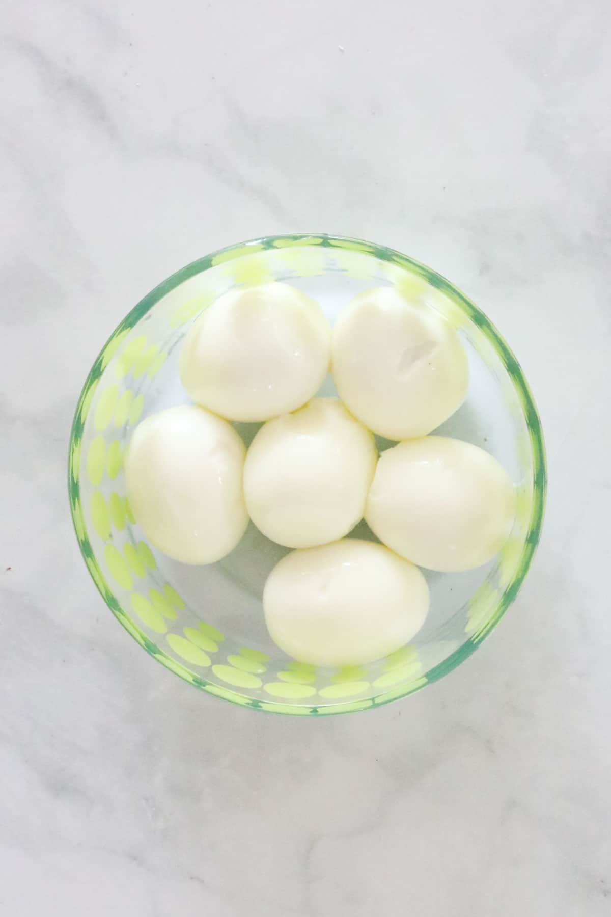 Peeled hard boiled eggs in a bowl.