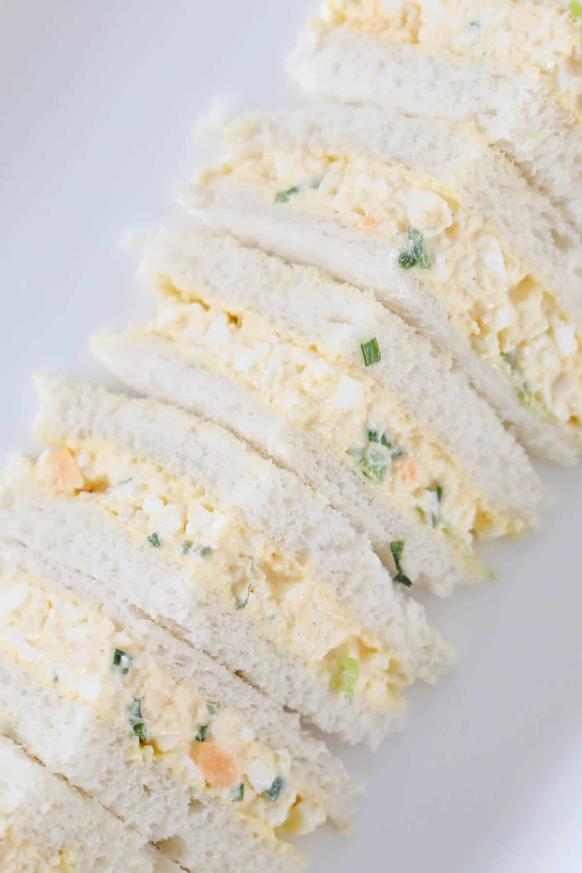 A row of egg sandwiches cut into triangles.