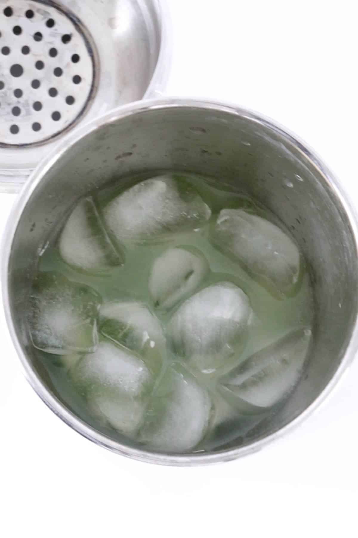 Cocktail shaker filled with ice cubes, Midori, lemon juice and cointreau.