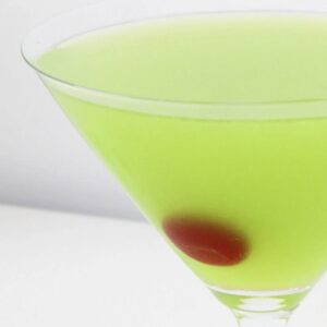 A glass filled with a green cocktail and a maraschino cherry.