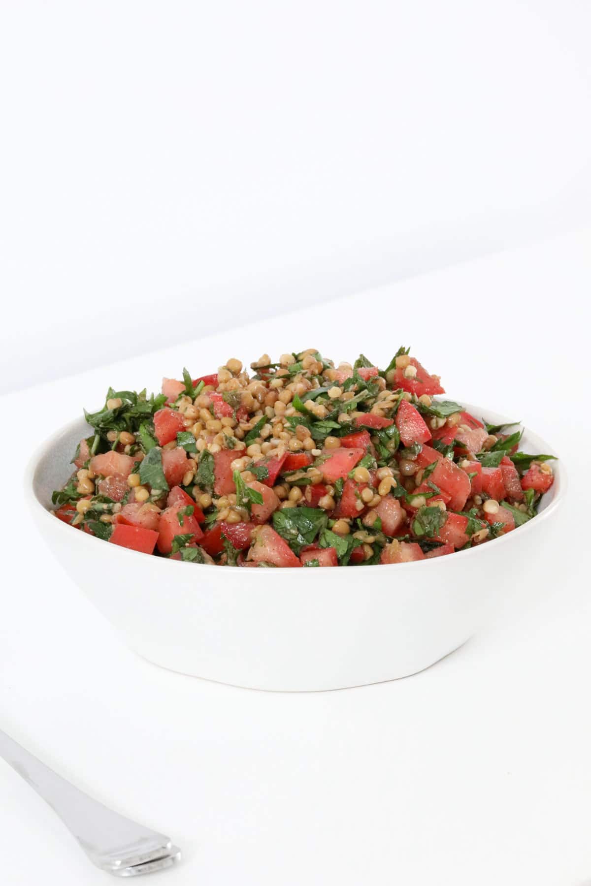 A white serving bowl filled with tabouli.