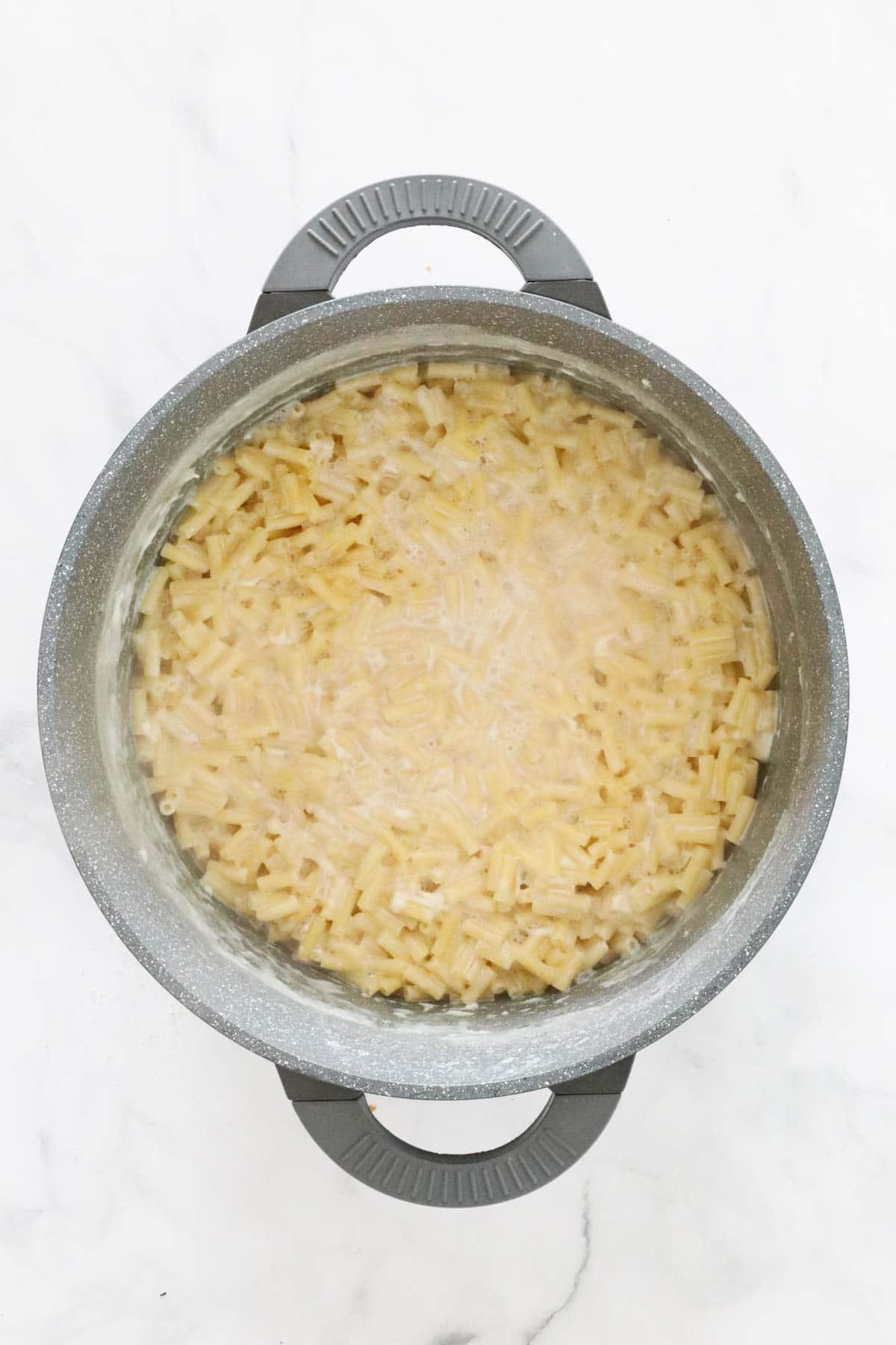 Macaroni pasta cooked in warm liquid in the pot.