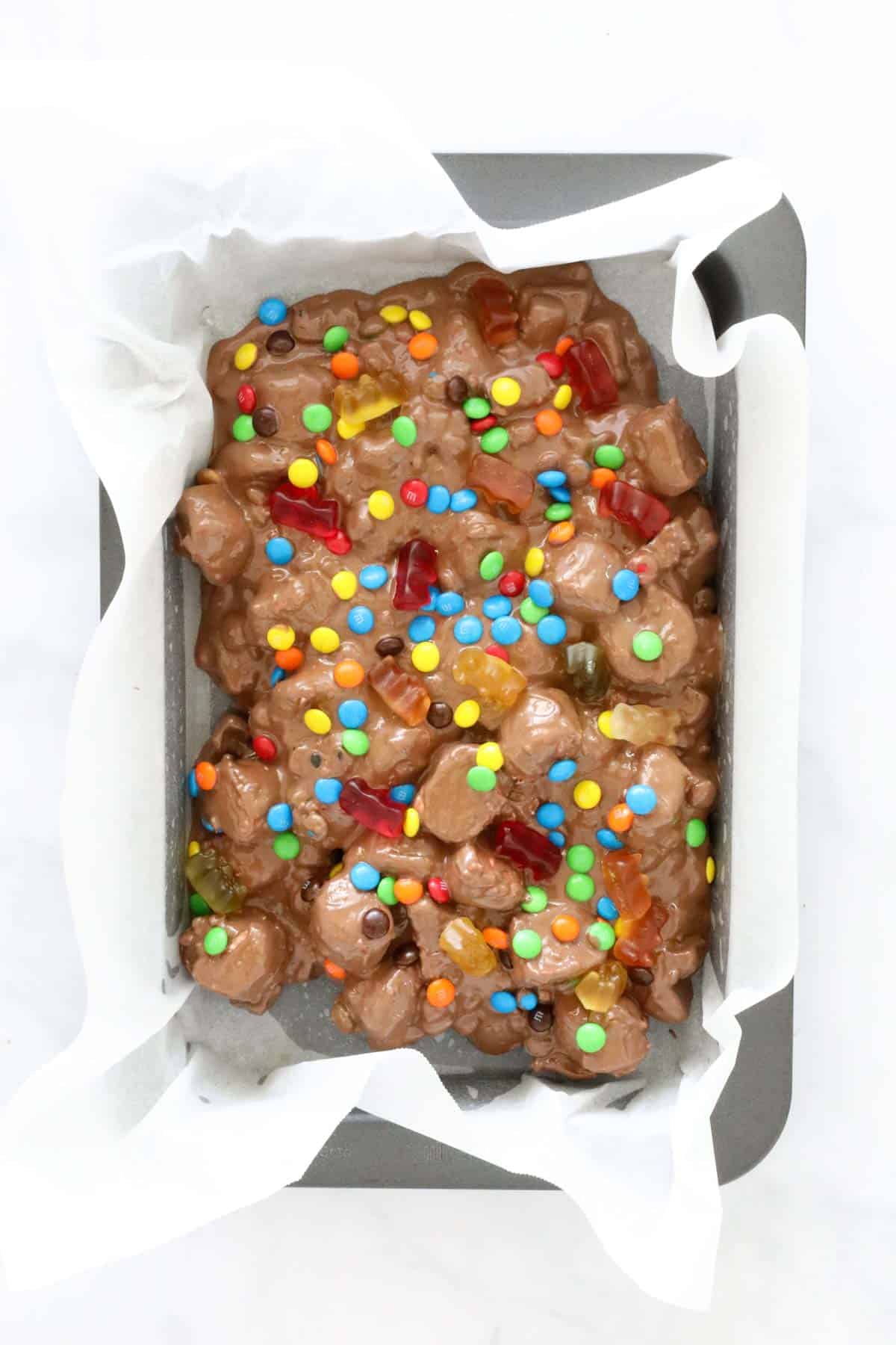 The rocky road mixture poured into a baking tray with mini M&M's sprinkled over the top.