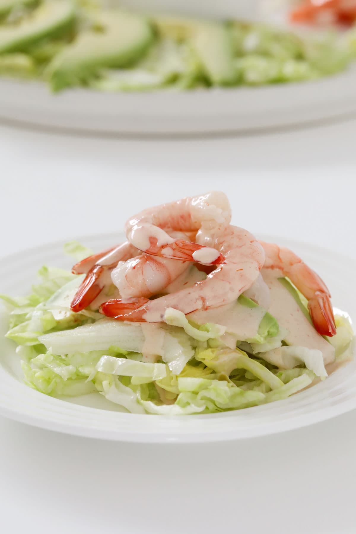 A small plate with a serving of prawn cocktail salad, the ain serving dish just visible behind.