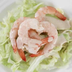 An overhead shot of a fresh prawn cocktail salad with ice berg lettuce, avocado and a creamy cocktail sauce.