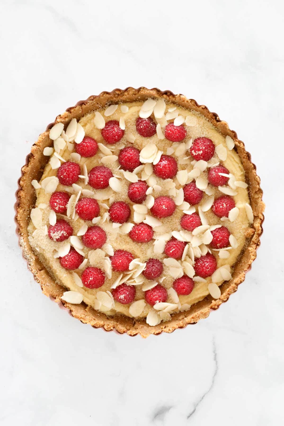 Raspberries pressed lightly into almond cream, and flaked almonds sprinkled over the top.