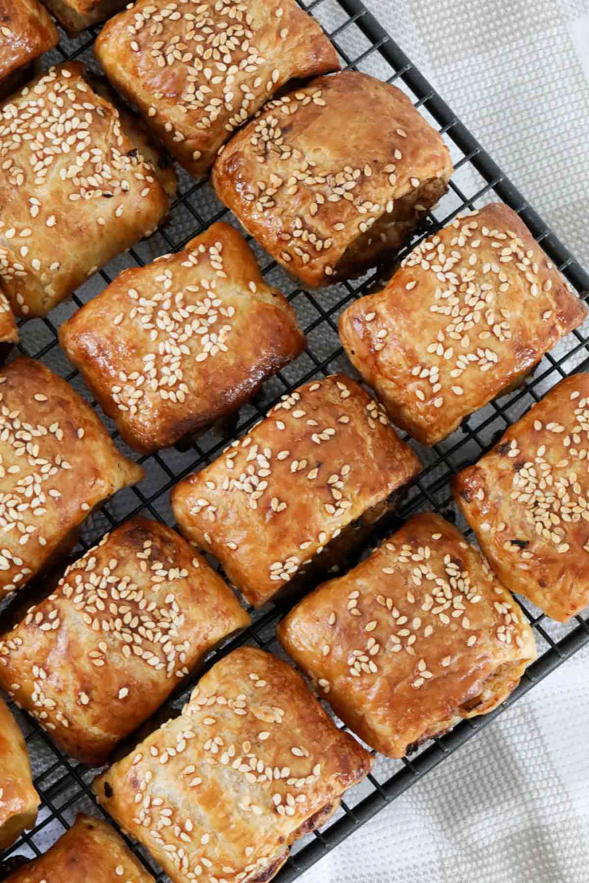 An overhead shot of sausage rolls cooling on a wire rack.