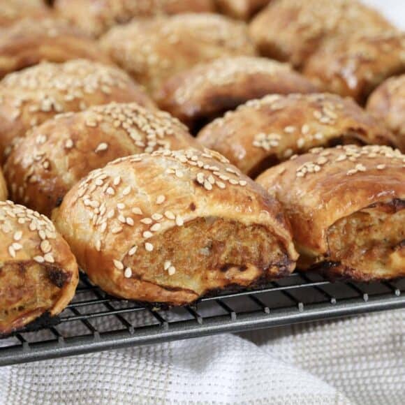 Crispy pork sausage rolls cooling on a wire rack.