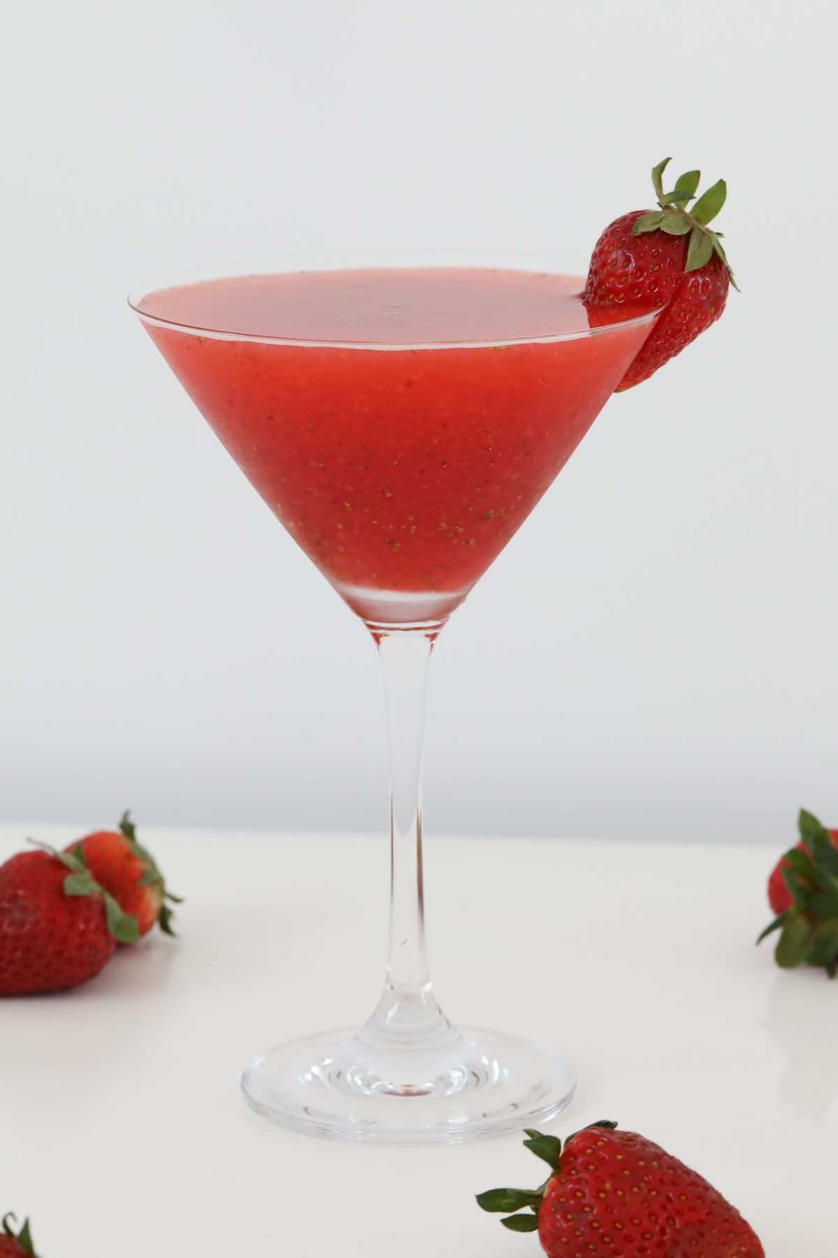 A martini glass filled with pureeed strawberry and vodka, then decorated with fresh strawberry.