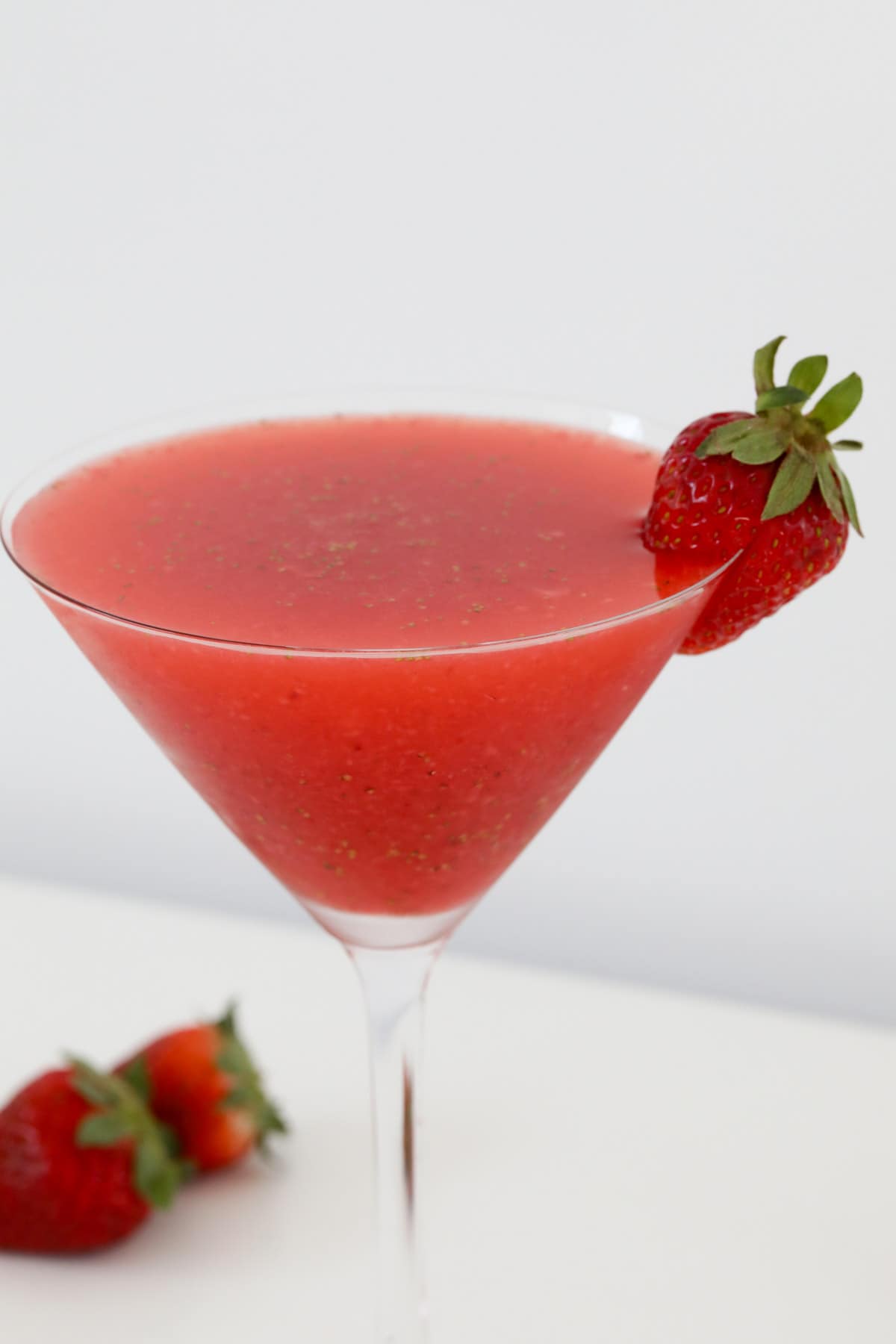 Strawberry cocktail in a martini glass garnished with a fresh strawberry.