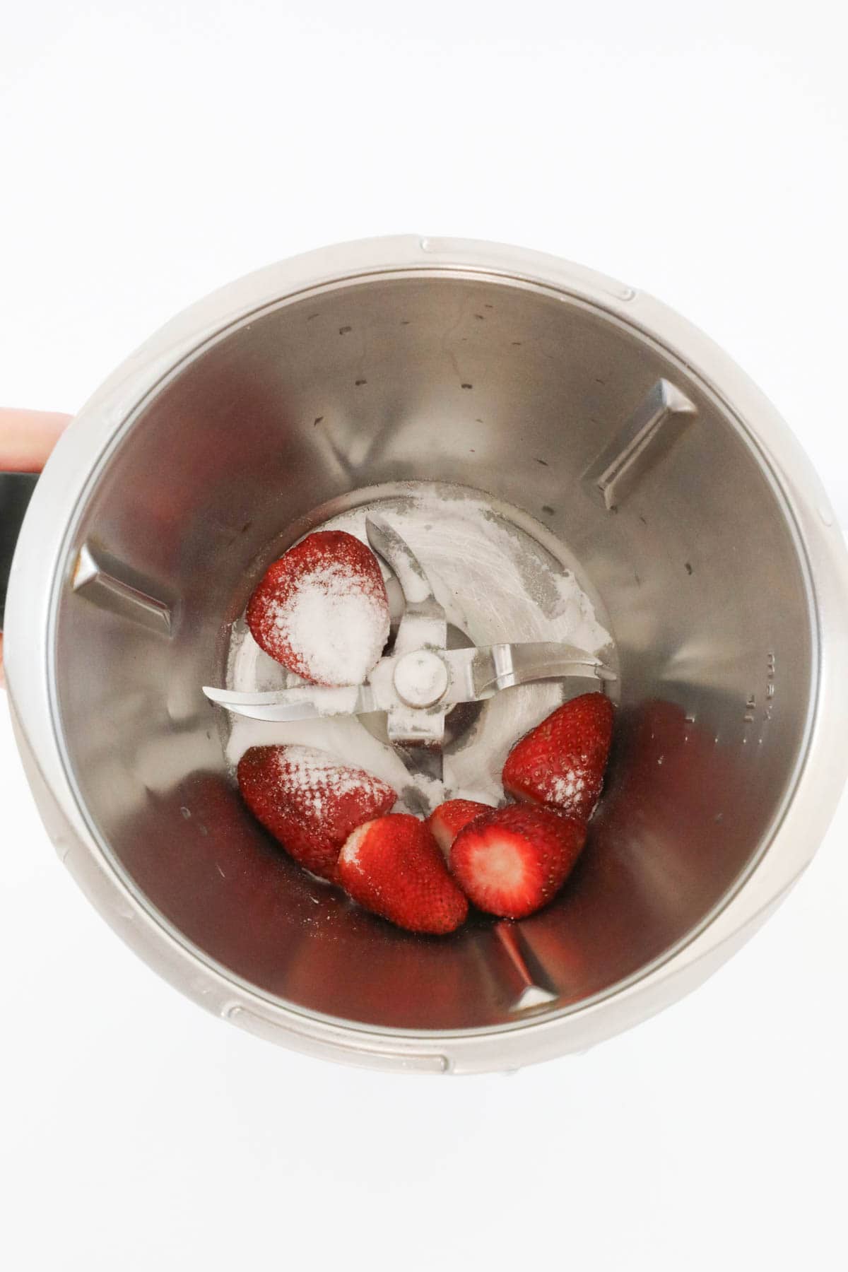 Fresh strawberries and caster sugar in the base of a blender.