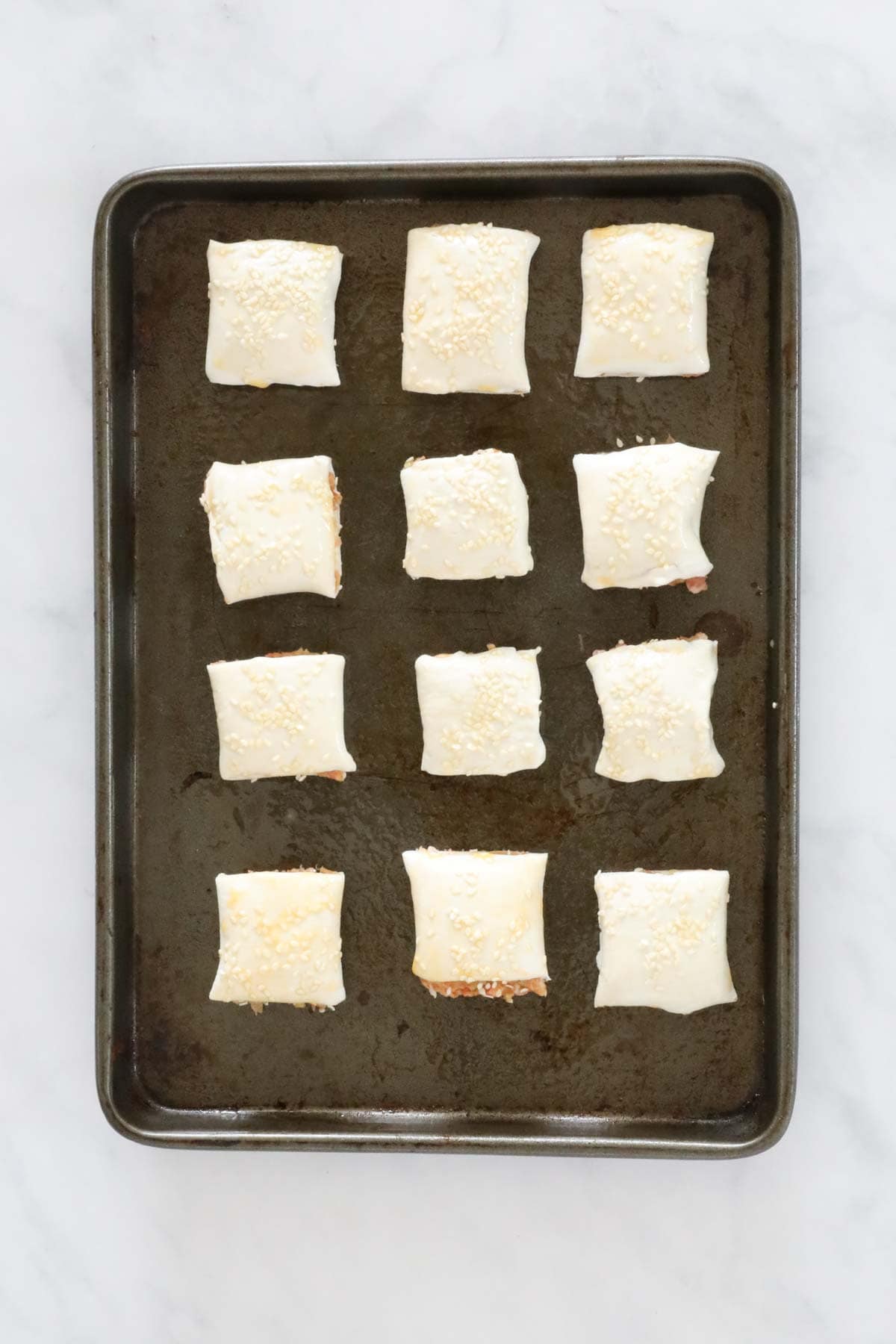 Unbaked sausage rolls on a tray.