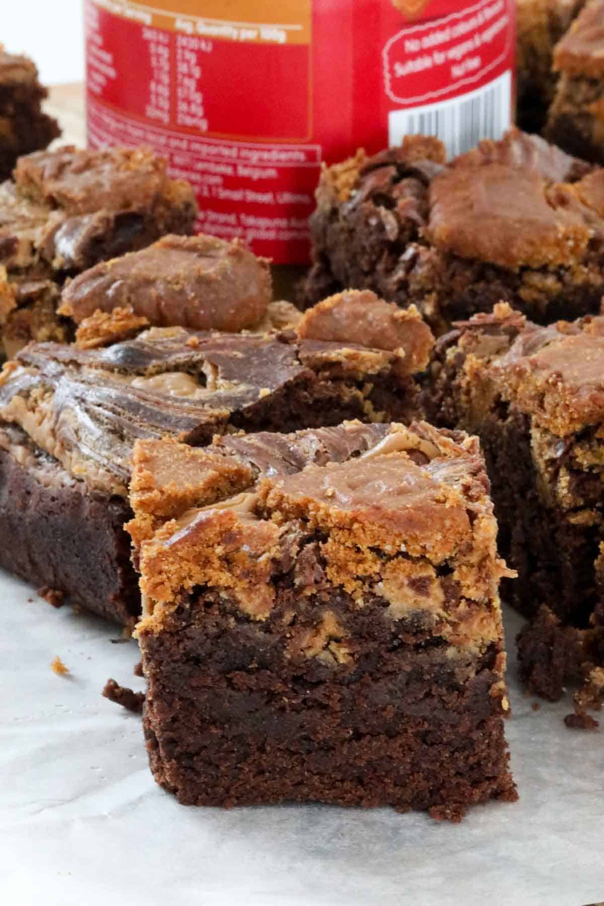 Brownie squares with a jar of Biscoff spread in the background.
