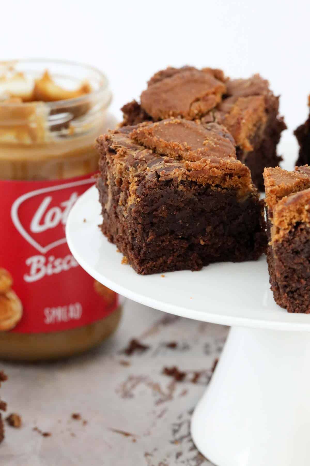 Biscoff brownie squares in front of a jar of spread.
