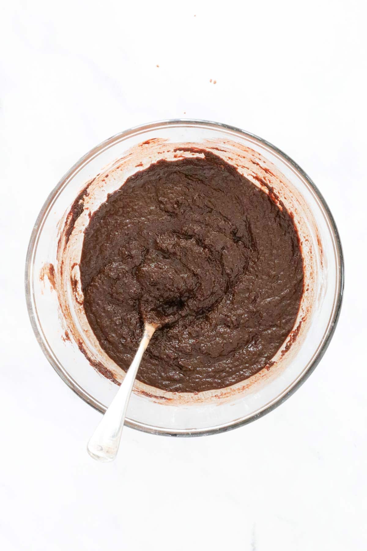 Cocoa and sugar mixed together with melted butter mixture in a glass bowl.